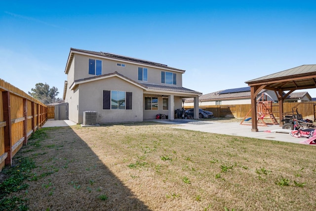 rear view of property featuring a gazebo, a fenced backyard, solar panels, and a patio