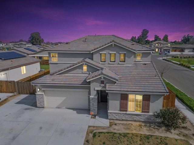 traditional-style home with stone siding, concrete driveway, and stucco siding