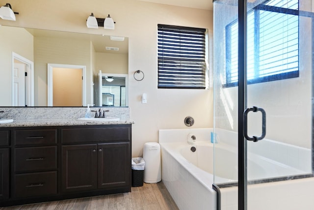 bathroom with wood finished floors, visible vents, a sink, a bath, and double vanity