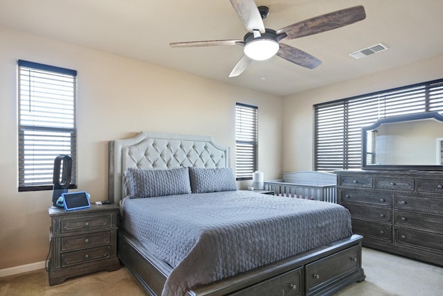 bedroom with a ceiling fan, visible vents, light carpet, and baseboards