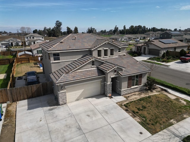 traditional-style house featuring stone siding, a residential view, a tiled roof, fence, and stucco siding