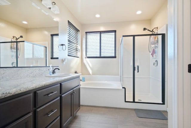 bathroom with a stall shower, a healthy amount of sunlight, vanity, and a bath