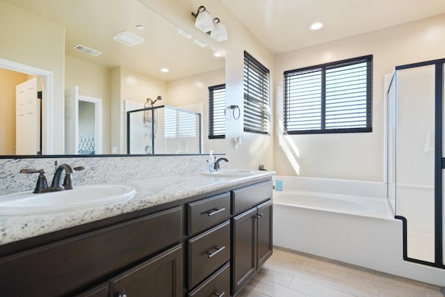 full bath with a bath, a sink, visible vents, and a shower stall