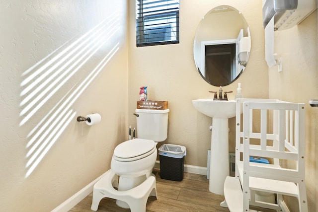 bathroom with wood finished floors, toilet, and baseboards