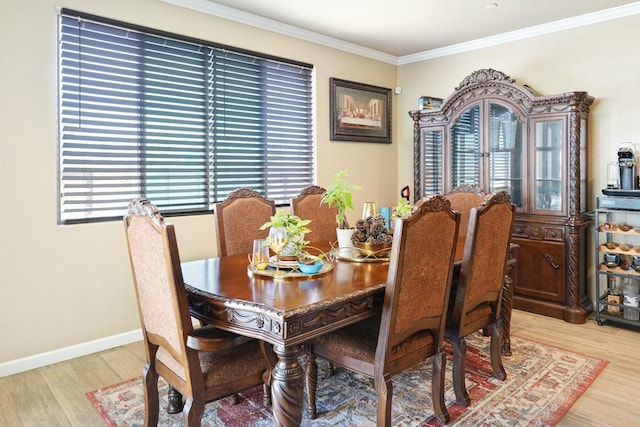 dining room featuring baseboards, crown molding, and light wood finished floors