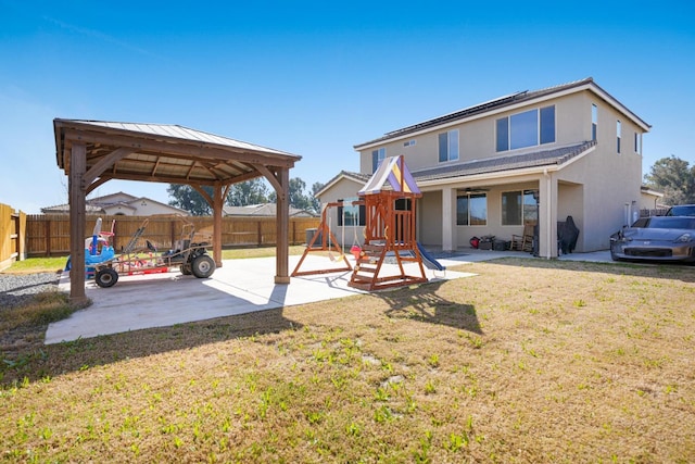 rear view of house with a playground, a yard, a patio area, and a fenced backyard