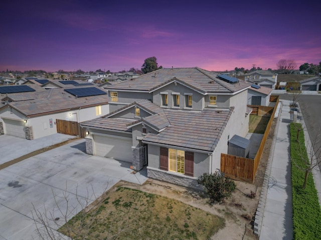 traditional-style house featuring concrete driveway, a tile roof, fence private yard, and stucco siding