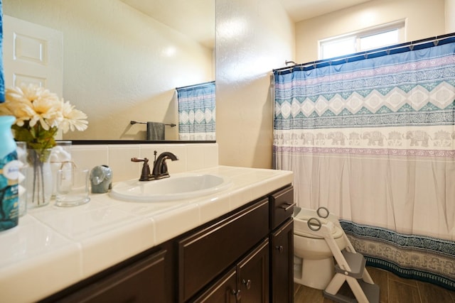 full bath featuring toilet, curtained shower, and vanity