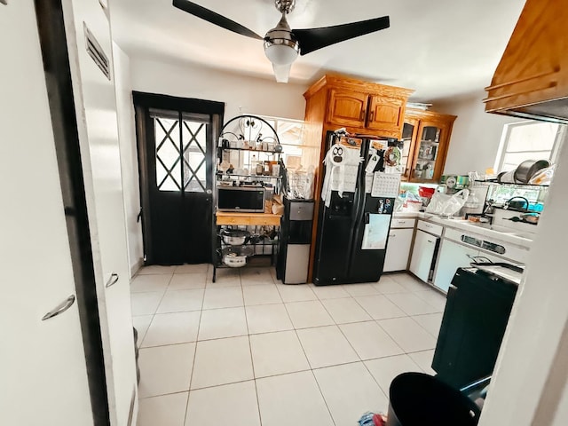 kitchen with light countertops, black refrigerator with ice dispenser, brown cabinetry, glass insert cabinets, and ceiling fan