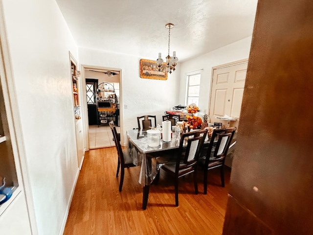 dining space featuring a chandelier, light wood finished floors, and baseboards