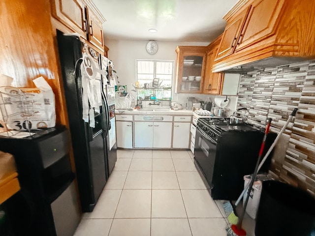 kitchen with light tile patterned floors, light countertops, black appliances, premium range hood, and backsplash