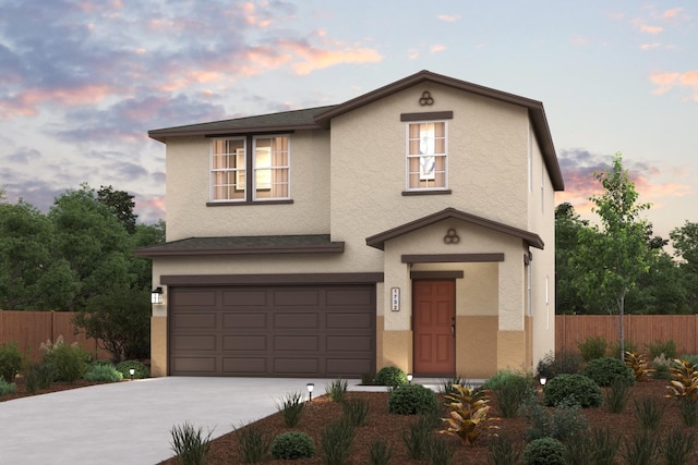 traditional-style house featuring an attached garage, fence, concrete driveway, and stucco siding