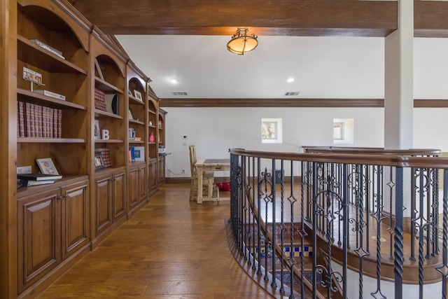 corridor featuring dark wood-style floors, baseboards, visible vents, and ornamental molding