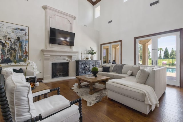 living area featuring hardwood / wood-style flooring, visible vents, a fireplace with raised hearth, and french doors