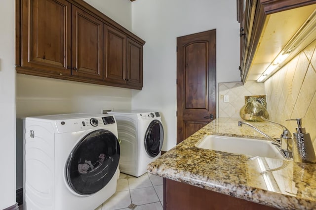 laundry room featuring light tile patterned floors, washing machine and clothes dryer, a sink, and cabinet space