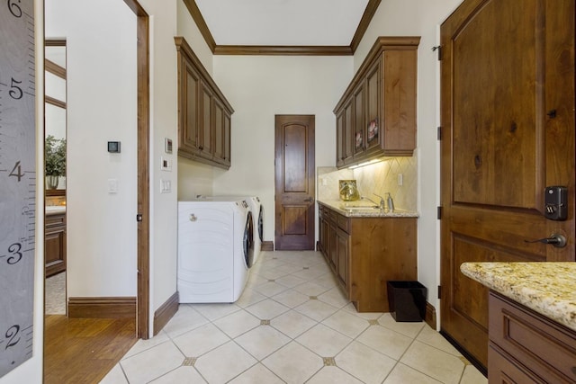 washroom featuring washer and clothes dryer, light tile patterned floors, cabinet space, ornamental molding, and baseboards