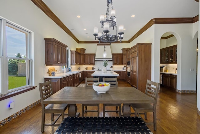 kitchen with dark wood-style floors, light countertops, decorative backsplash, an inviting chandelier, and a sink