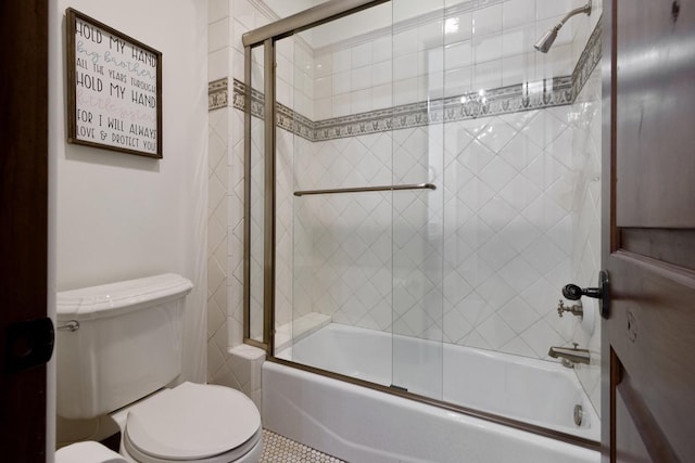 bathroom featuring toilet and shower / bath combination with glass door