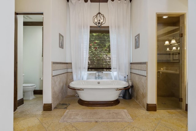 bathroom featuring a stall shower, a freestanding bath, tile walls, and toilet