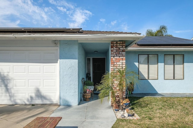 view of exterior entry with solar panels, an attached garage, and stucco siding