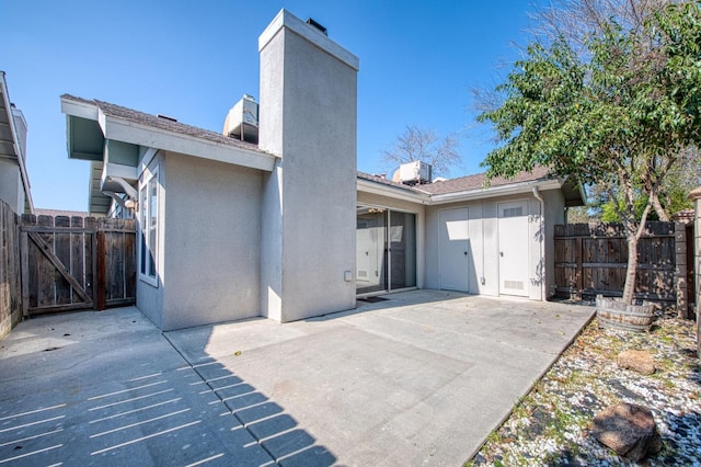 rear view of house featuring a chimney, a patio area, fence, and stucco siding