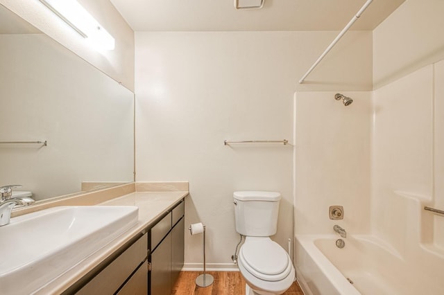 bathroom with toilet, washtub / shower combination, vanity, wood finished floors, and baseboards