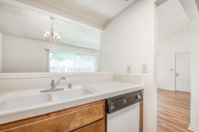 kitchen with light wood-style flooring, brown cabinetry, vaulted ceiling, a textured ceiling, and dishwasher