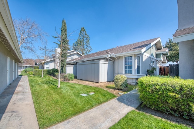 view of side of home featuring a lawn and fence