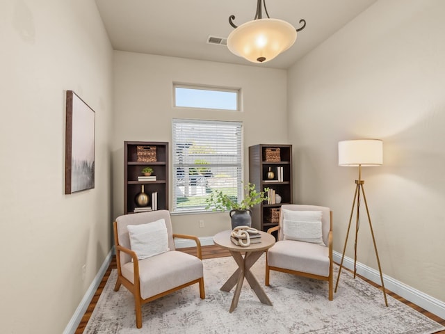 living area with visible vents, baseboards, and wood finished floors