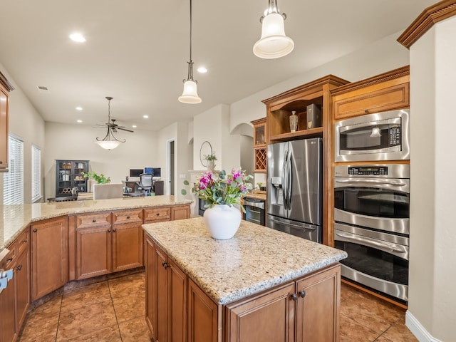 kitchen with stainless steel appliances, brown cabinets, hanging light fixtures, and light stone counters