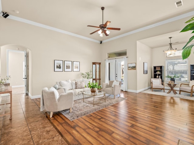 living room featuring arched walkways, ornamental molding, hardwood / wood-style flooring, and visible vents