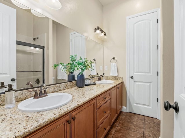 bathroom featuring double vanity, an enclosed shower, a sink, and tile patterned floors