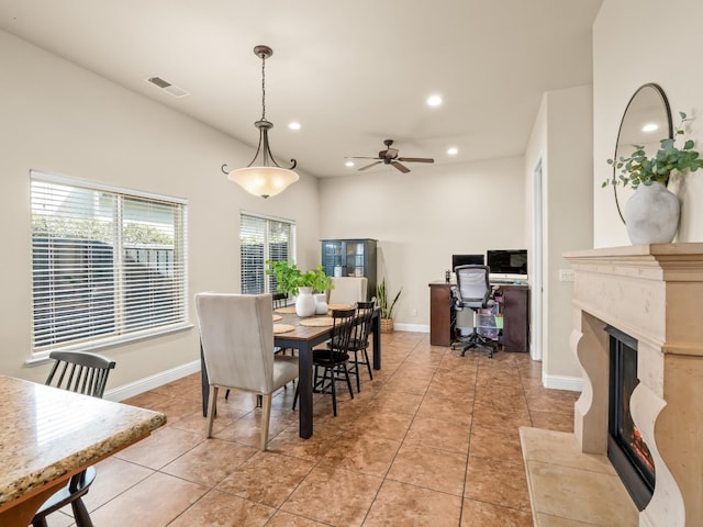 dining area with a fireplace with raised hearth, light tile patterned floors, recessed lighting, visible vents, and baseboards