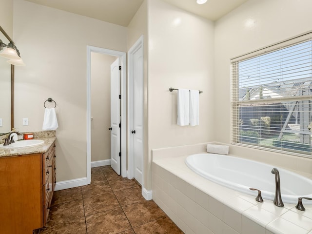 full bath featuring tile patterned floors, baseboards, a bath, and vanity