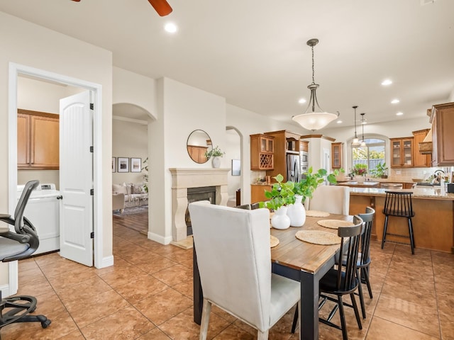 dining area with arched walkways, a ceiling fan, washer / clothes dryer, a fireplace, and recessed lighting