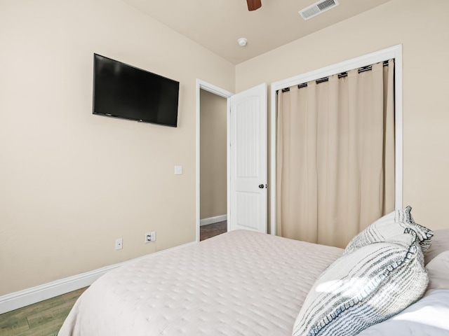 bedroom featuring baseboards, visible vents, ceiling fan, and wood finished floors