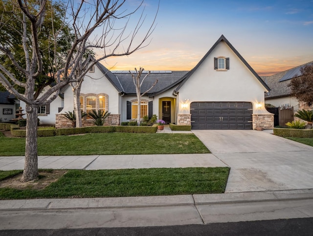 view of front of property featuring driveway, stone siding, a lawn, and stucco siding