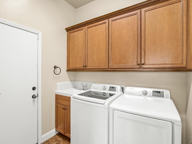 clothes washing area with cabinet space, a sink, washer and clothes dryer, and baseboards