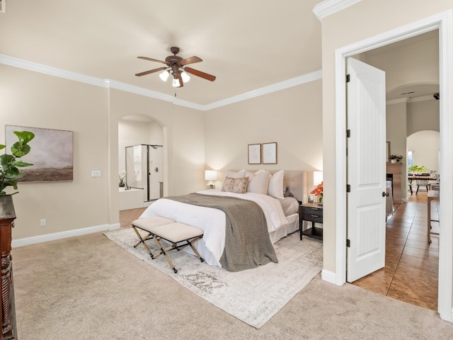 carpeted bedroom with tile patterned flooring, baseboards, arched walkways, and crown molding