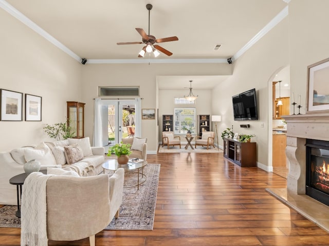 living room featuring ornamental molding, a glass covered fireplace, hardwood / wood-style flooring, and baseboards