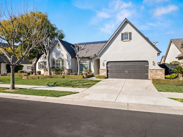 view of front of house with a front yard, stone siding, driveway, and solar panels