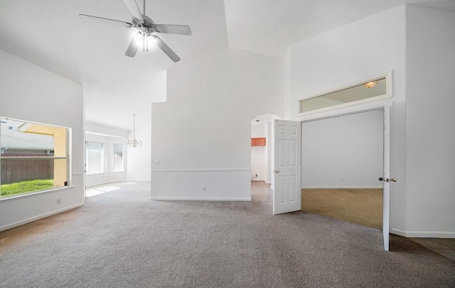 unfurnished bedroom featuring arched walkways, a high ceiling, carpet, and baseboards