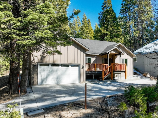 40865 Cold Springs Ln, Shaver Lake, CA 93664 - view of front of home with a wooden deck, driveway, board and batten siding, a shingled roof, and an attached garage