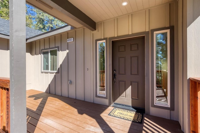 entrance to property featuring board and batten siding and roof with shingles