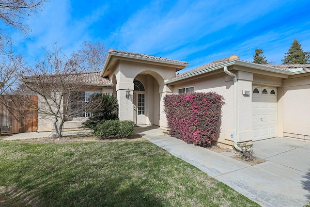 view of front of house with a garage, a tile roof, a front lawn, and stucco siding