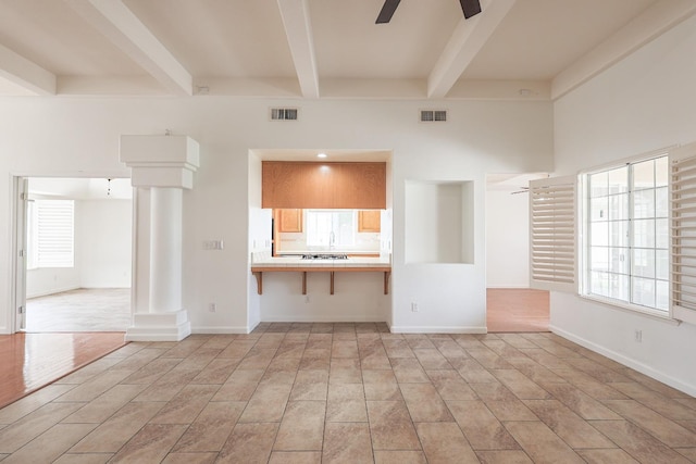 unfurnished living room with a ceiling fan, visible vents, and ornate columns