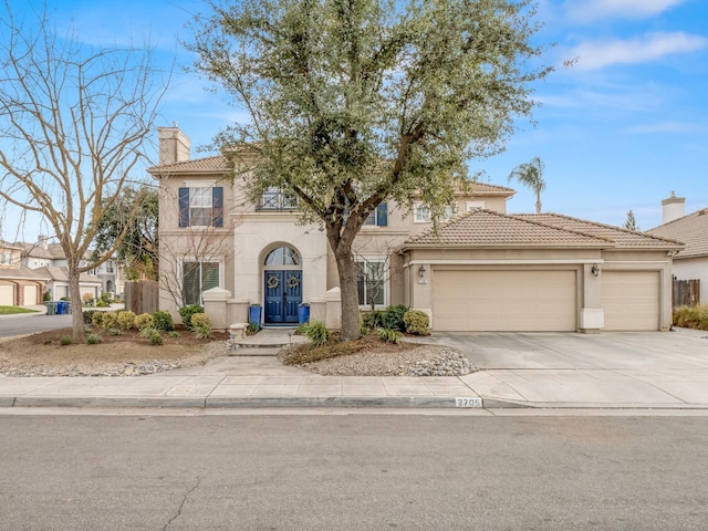 mediterranean / spanish home with a garage, a tiled roof, concrete driveway, and stucco siding