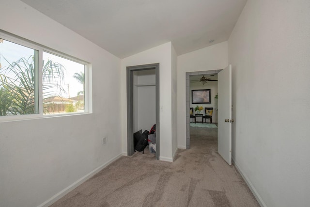 unfurnished bedroom with vaulted ceiling, light carpet, and baseboards