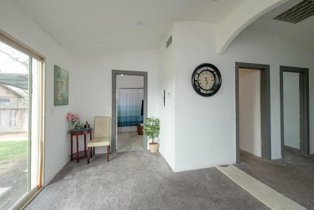 interior space with carpet floors, lofted ceiling, visible vents, and arched walkways