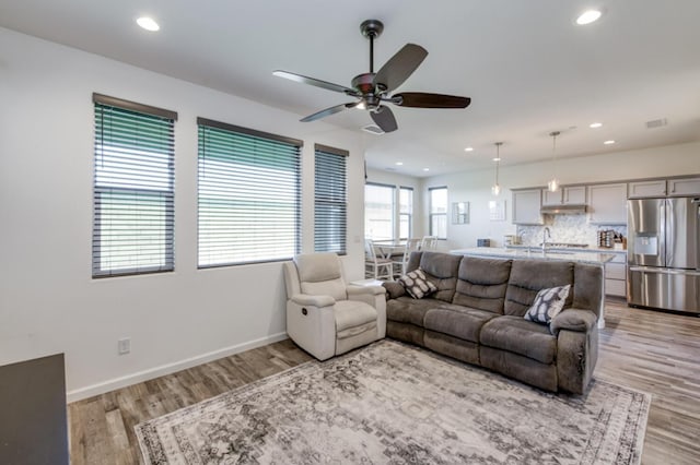 living room with light wood finished floors, ceiling fan, baseboards, and recessed lighting